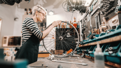 Woman bike shop owner working on wheel in her store